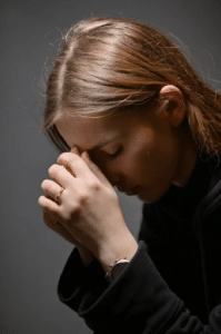Woman bowing her head in prayer with hands clasped