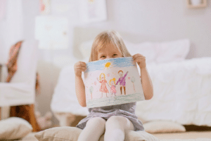 Young child holding a colorful family drawing, representing creative learning at Coker Early Learning Center in San Antonio