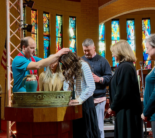 Pastor praying over a young woman during a baptism ceremony inside Coker Methodist Church sanctuary in San Antonio.