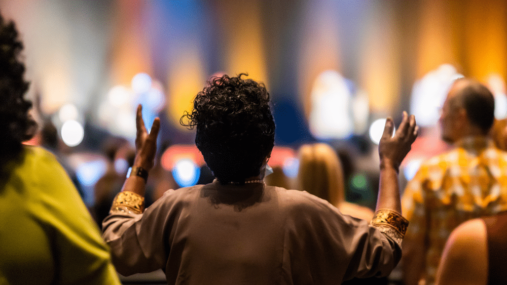 Congregation attending a Methodist or Baptist church service, hands raised in worship and prayer.