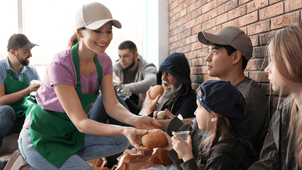 Woman volunteering, handing food to people, emphasizing the heart of giving and community support