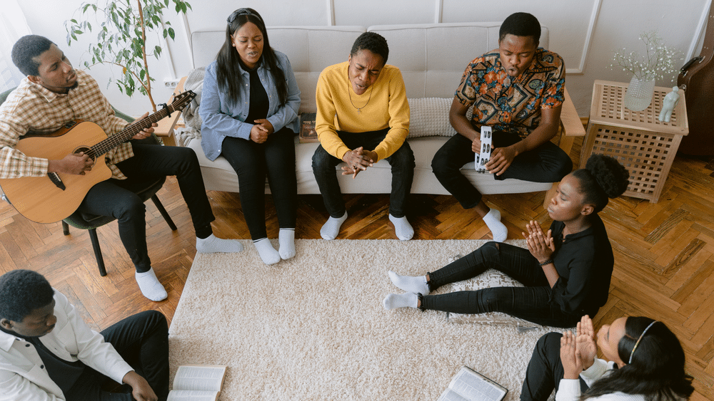 People sitting in a circle worshipping and reading scriptures together indoors.