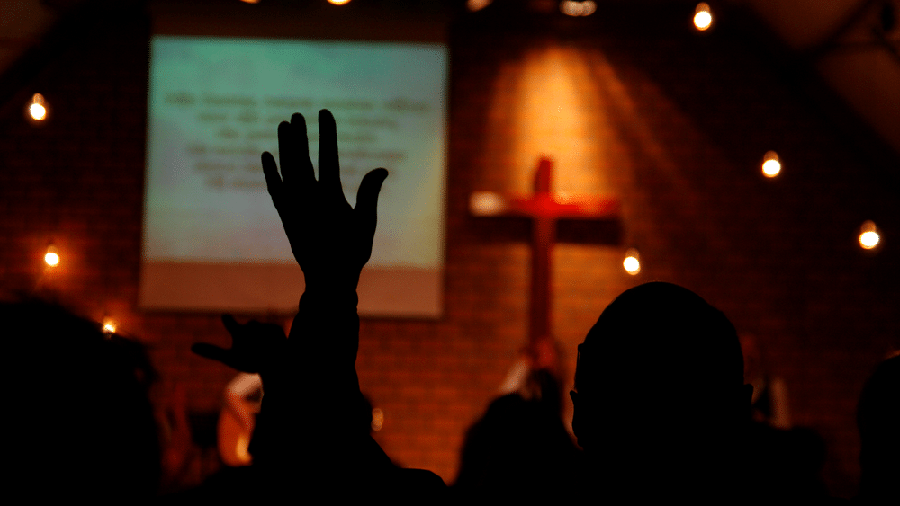 Person raising hand in Methodist church worship service